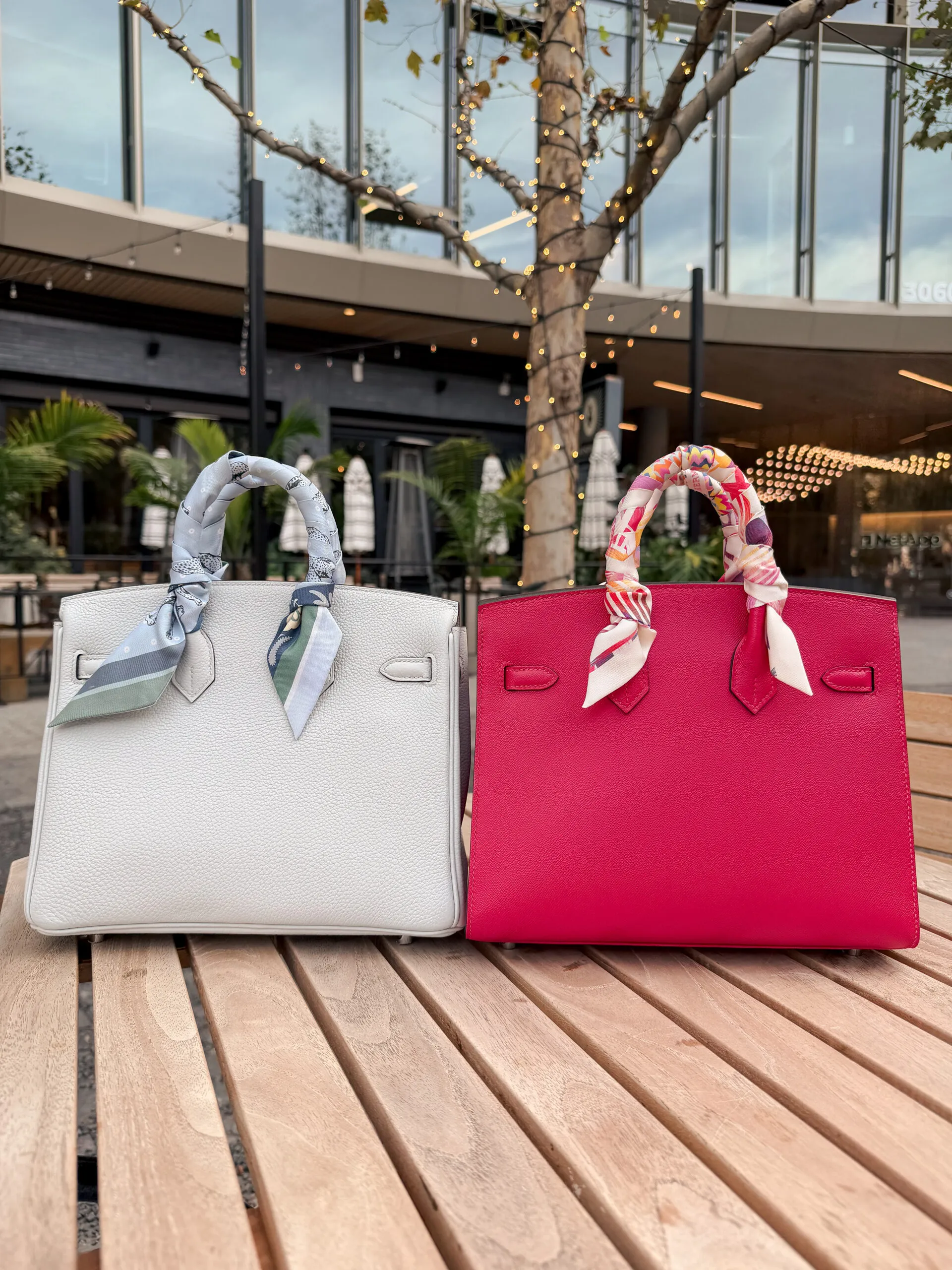 Back view of the white Togo Retourne and rose Epsom Sellier Birkins on a slatted wooden table