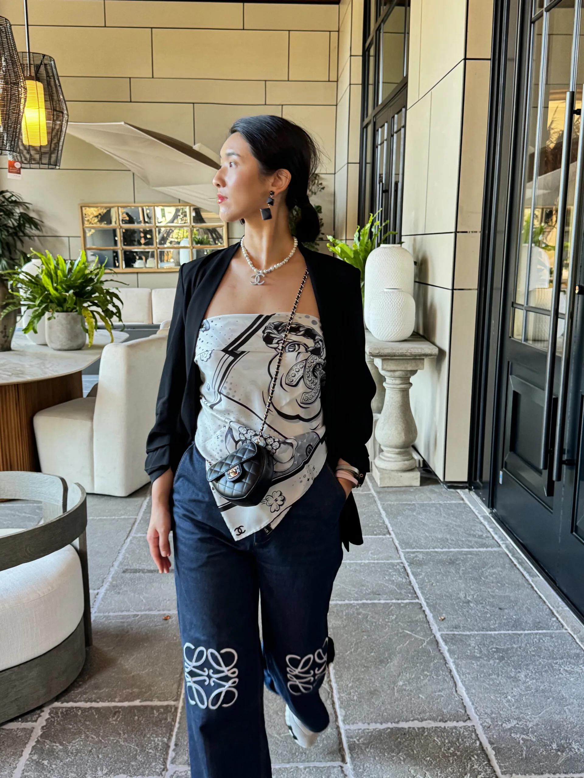Lily in a Chanel silk bandeau, black blazer and logo-embroidered jeans with a Chanel belt bag
